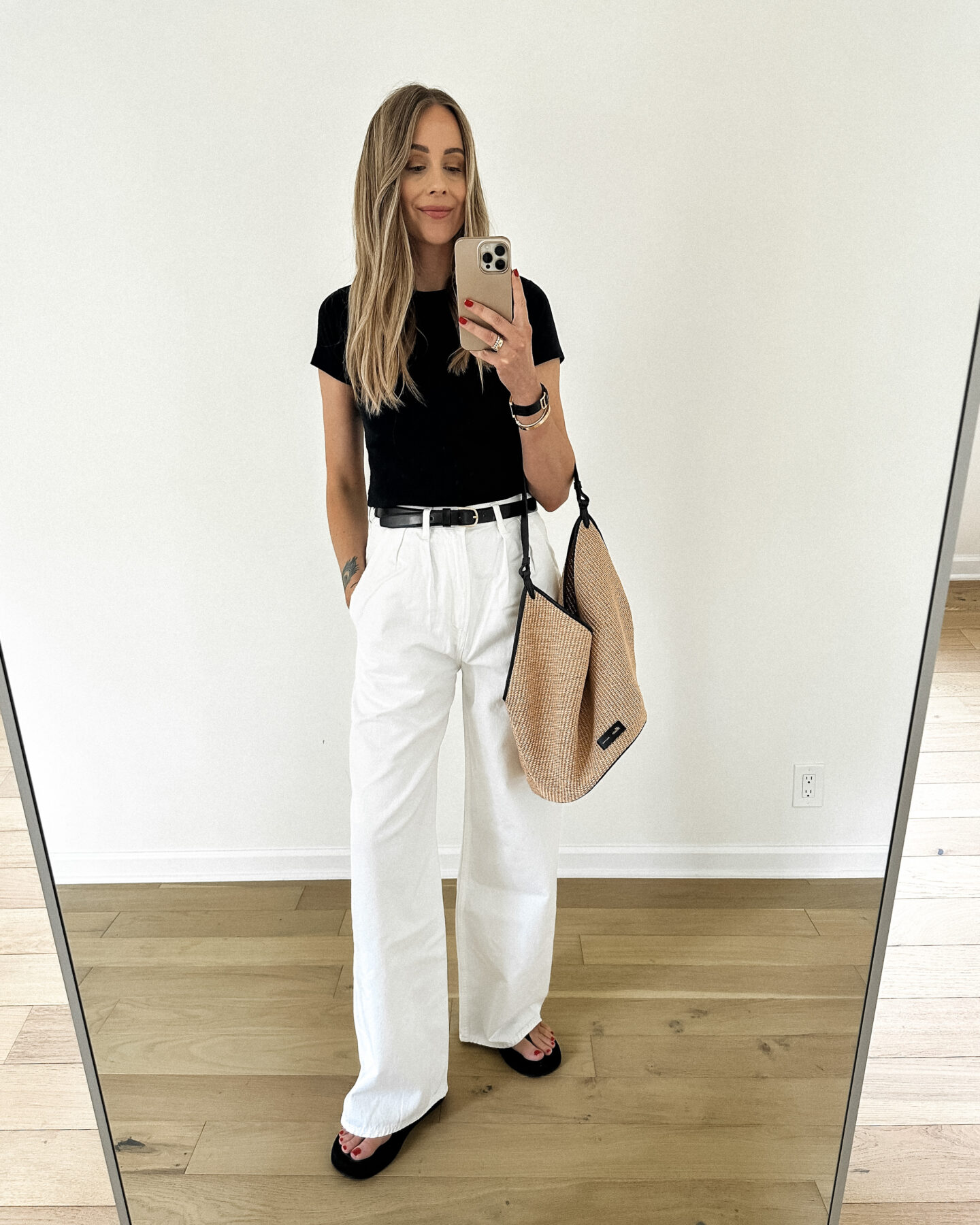 Fashion Jackson wearing short sleeve black tee Citizens of Humanity Maritzy Pleated Trouser Jeans White The Row Giza Black Sandals Black Belt Khaite Medium Lotus Raffia Tote Summer Outfit