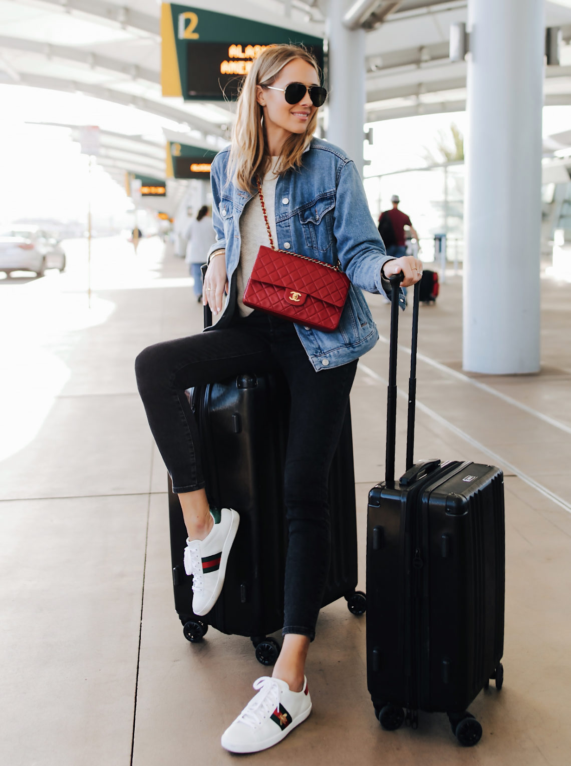 Fashion Jackson Airport Style Wearing Denim Jacket Black Skinny Jeans Gucci Sneakers Red Chanel Handbag Calpak Black Ambeur Spinner Luggage Set Featured Image