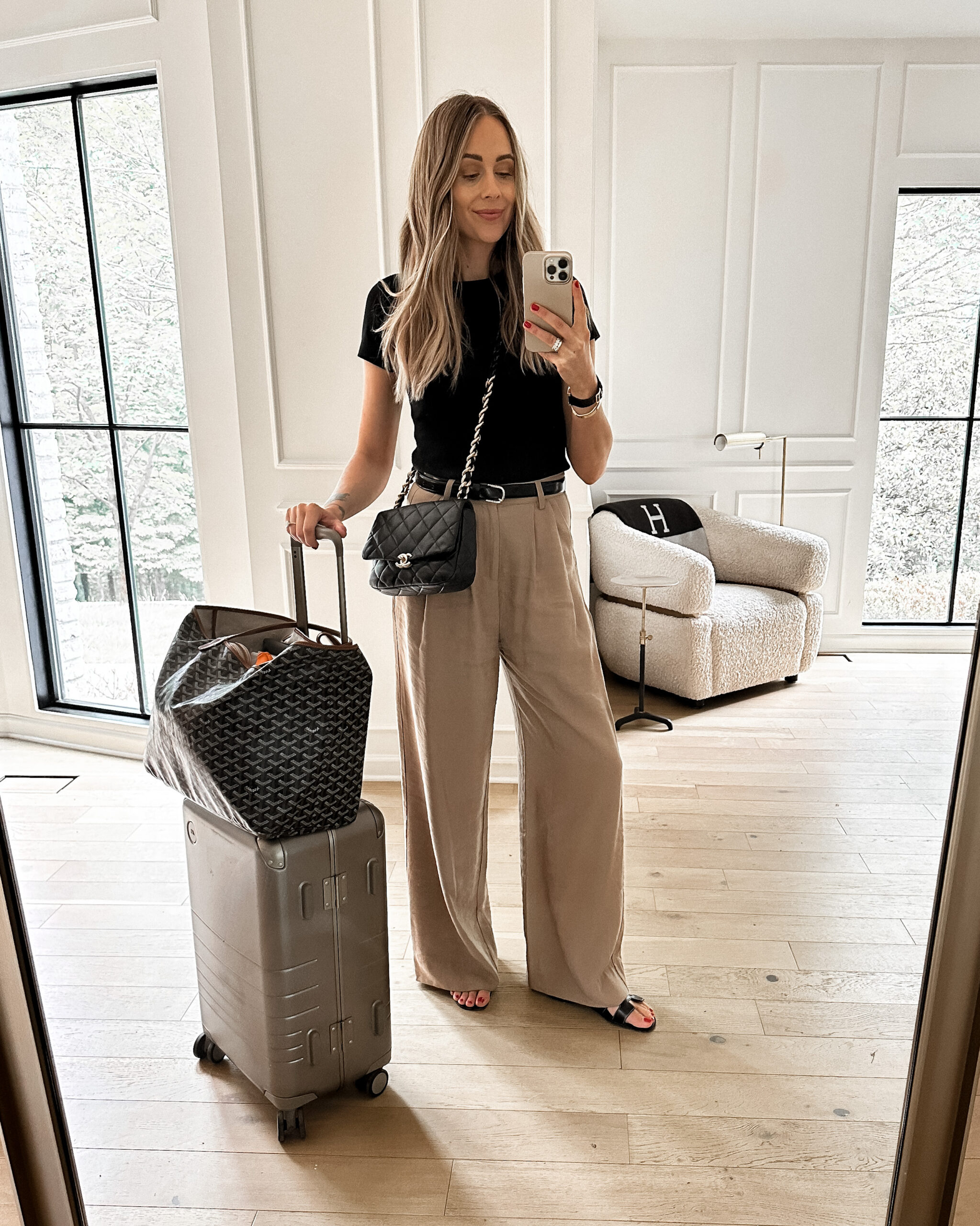 Fashion Jackson Wearing Short Sleeve Black Tee Tan Wide Leg Pants Black Hermes Oran Sandals Black Chanel Handbag Monos Carry-On Luggage Goyard GM Tote