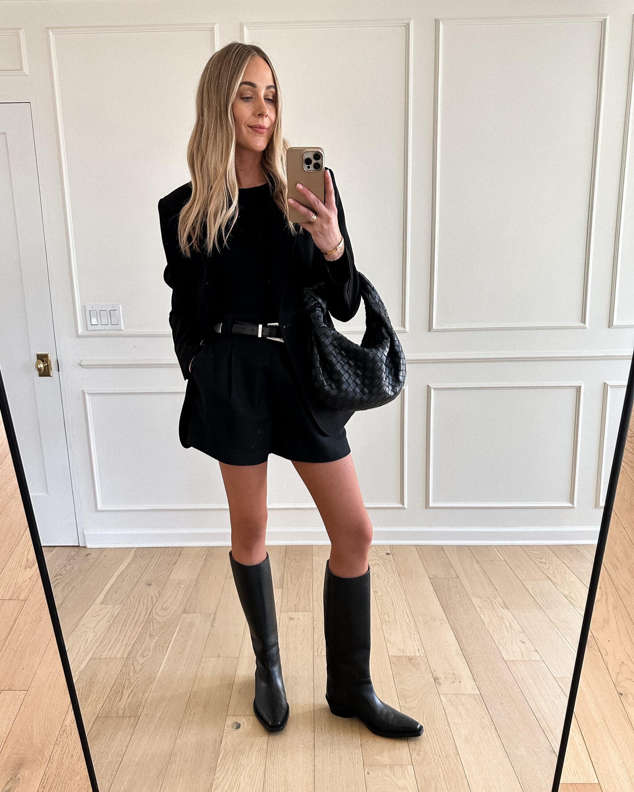 Fashion Jackson Wearing MAYSON the label black boyfriend blazer, MAYSON the label black trouser shorts, black top, Khaite black silver belt, Proenza Schouler Bronco Black Knee High Boots, black blazer and shorts outfit, black blazer outfit inspo