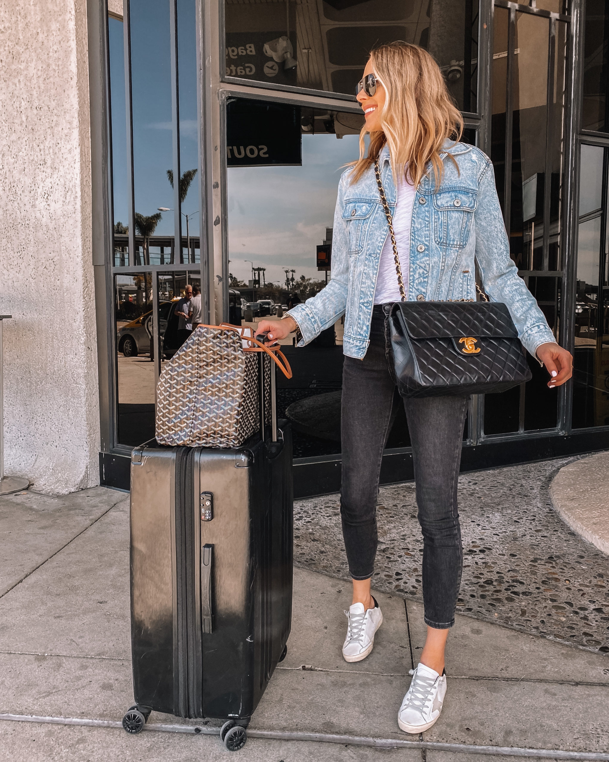 Fashion Jackson Wearing Denim Jacket Black Skinny Jeans Golden Goose Sneakers Chanel XL Jumbo Black Handbag Calpak Luggage Goyard Tote Travel Outfit