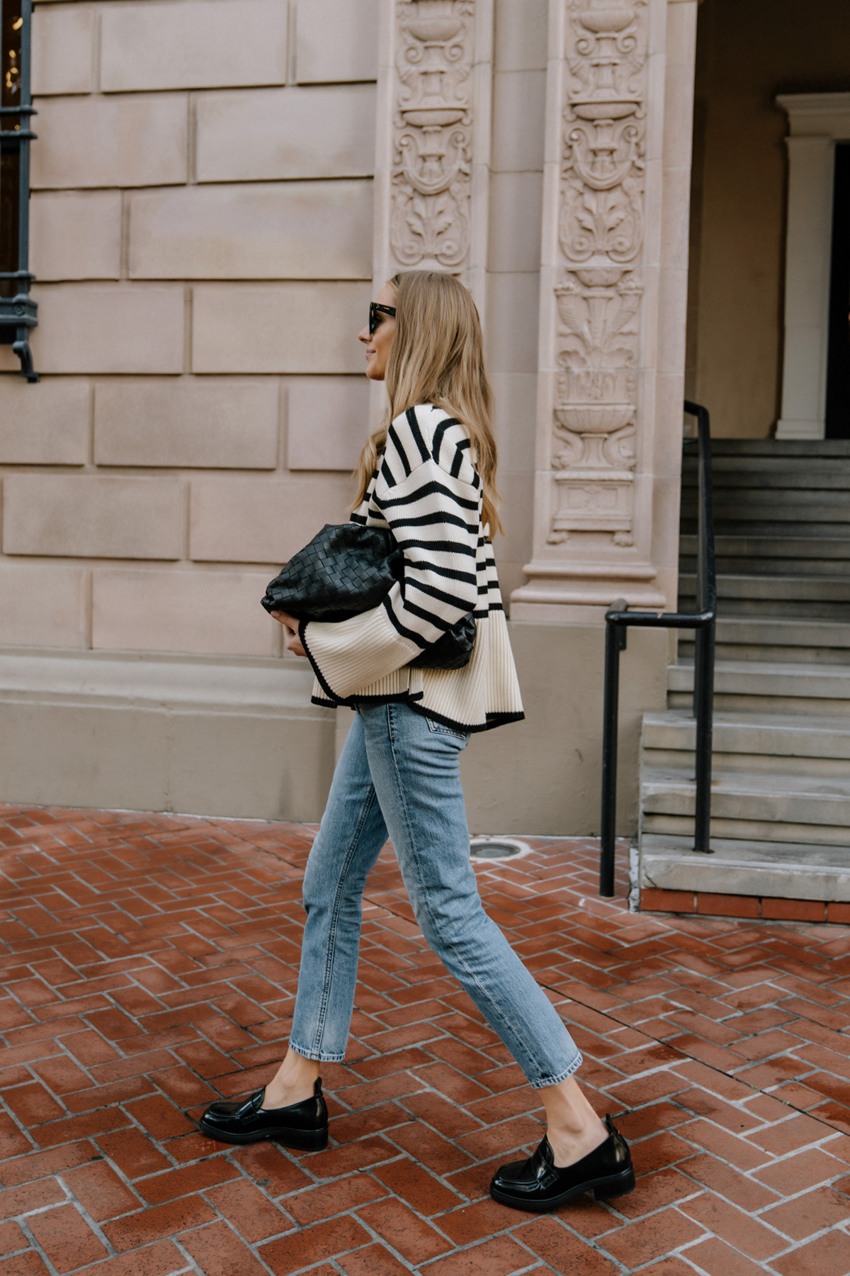 Fashion Jackson Wearing Toteme Striped Oversized Sweater Outfits Black Loafer Outfit AGOLDE Jeans Bottega Veneta Pouch Black Street Style Toteme Signature Striped Sweater Review