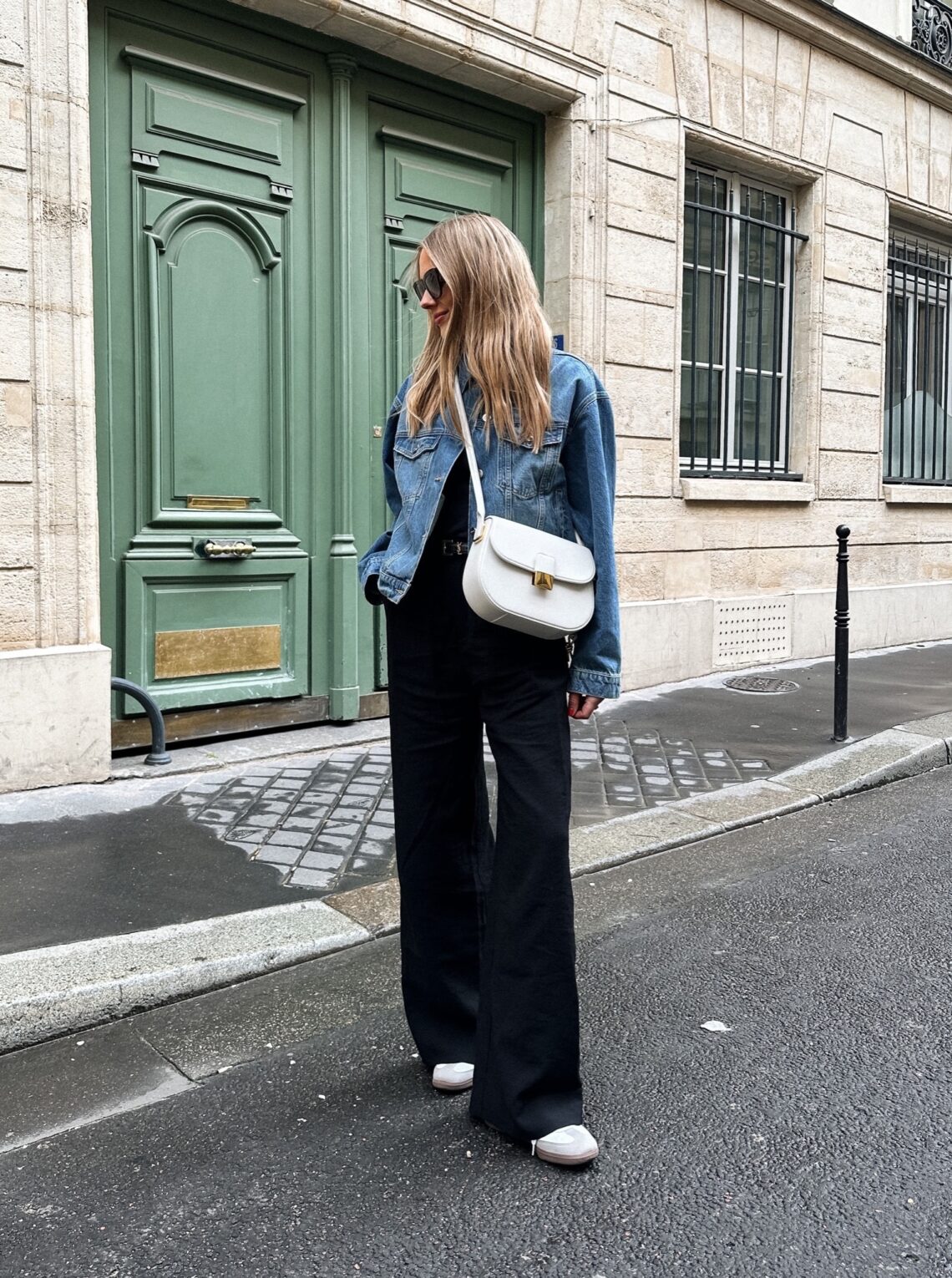 Fashion Jackson wearing denim jacket spring capsule black wide leg pants adidas sneakers white bottega handbag spring outfit